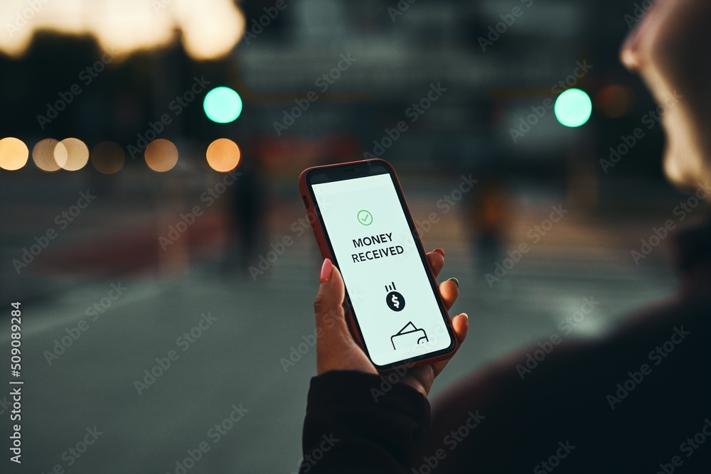 Money transfer. Online banking. Person transferring money online using applications to send and receive money on smartphones. Smartphone screen displaying money transfer confirmation