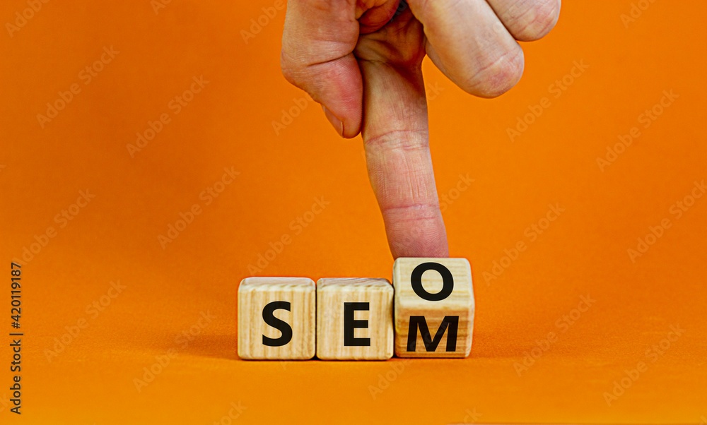 SEO vs SEM symbol. Businessman turns a cube and changes words SEO, Search Engine Optimization to SEM, Search Engine Matketing. Business, SEO vs SEM Concept. Beautiful orange background, copy space.