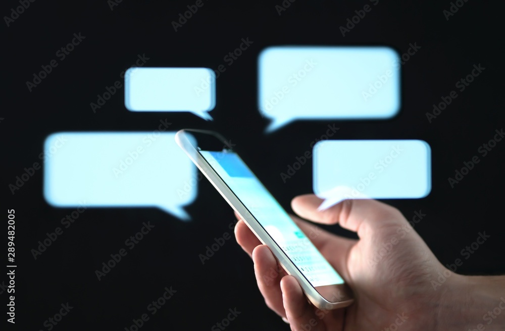 Text messages in cellphone screen with abstract hologram speech bubbles. Instant messaging app. Texting, group chat, sexting or sms concept. Customer service help desk with live support chatbot.